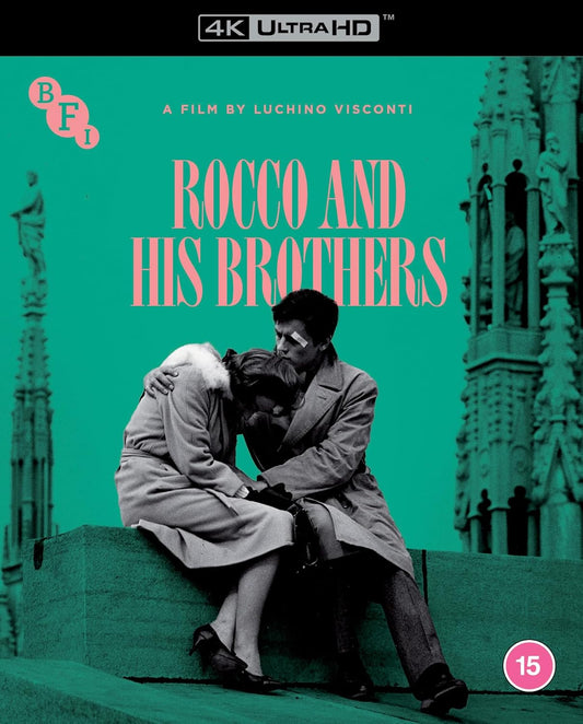 A couple sits together on a ledge against a teal background with cathedral spires.
