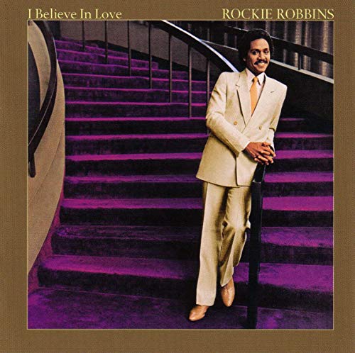 Album cover with man in beige suit on purple staircase, brown border.