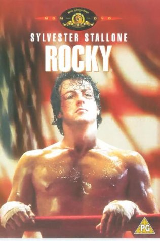 Sweaty shirtless man with bandaged hands leaning on red boxing ring ropes.