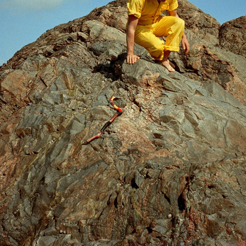 Album cover featuring a person on rocks with a snake-like object.