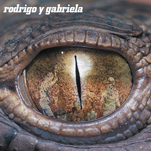 The alt text for the image is: "Close-up of a reptile's eye with the text 'rodrigo y gabriela'."
