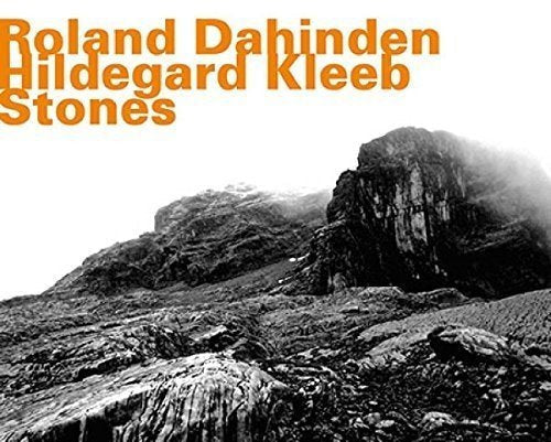"Album cover with orange text on white background, featuring black and white rocky landscape."