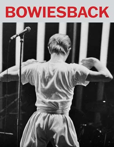 Black and white photo of David Bowie performing, seen from behind.