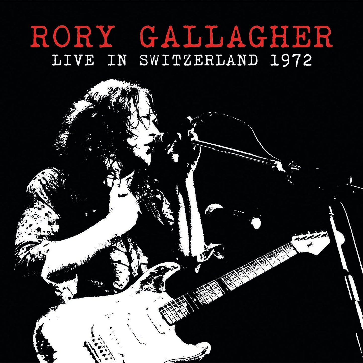 Rory Gallagher playing guitar and singing into a microphone, black and white.