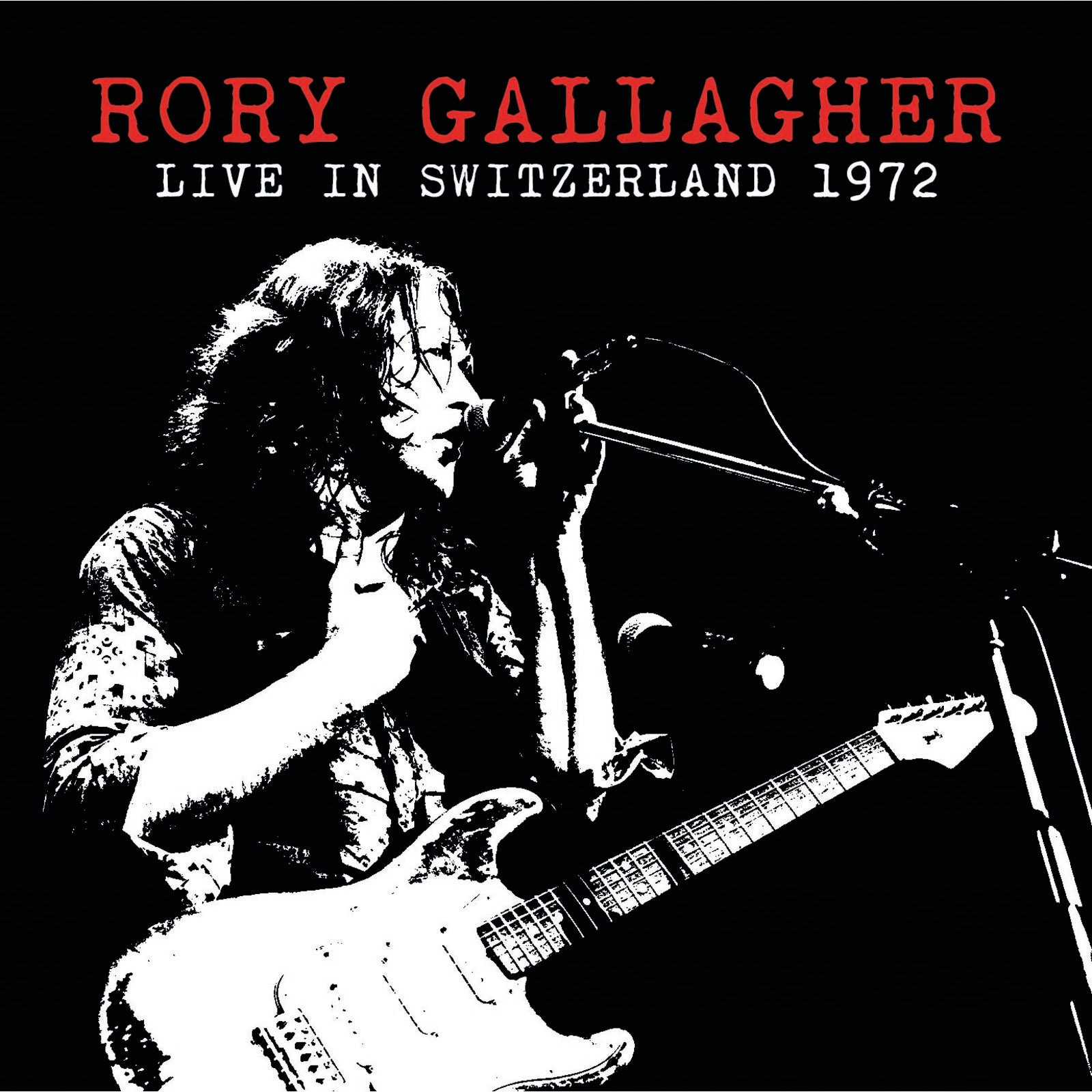 Rory Gallagher playing guitar and singing into a microphone, black and white.