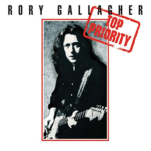 Black and white photo of Rory Gallagher with guitar and red priority stamp overlay.