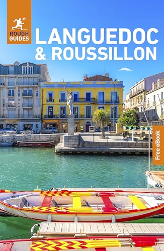 A canal with colorful rowing boats in front of yellow buildings in Languedoc, France.