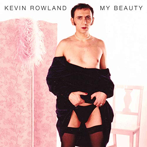 Album cover: man in black lingerie and stockings, with robe, standing by a pink screen.