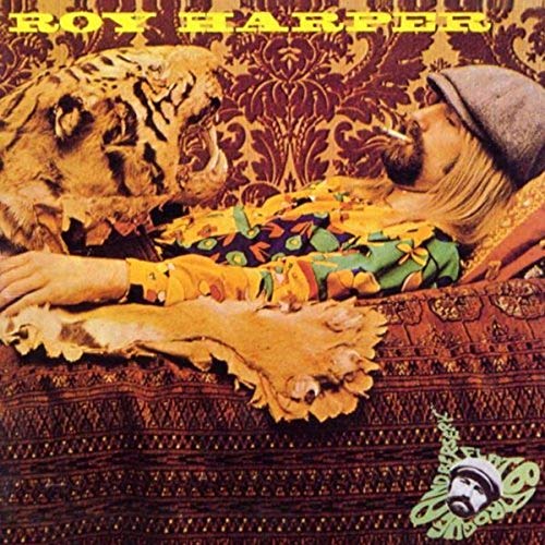 Album cover: Roy Harper with a tiger, reclining on patterned fabric.