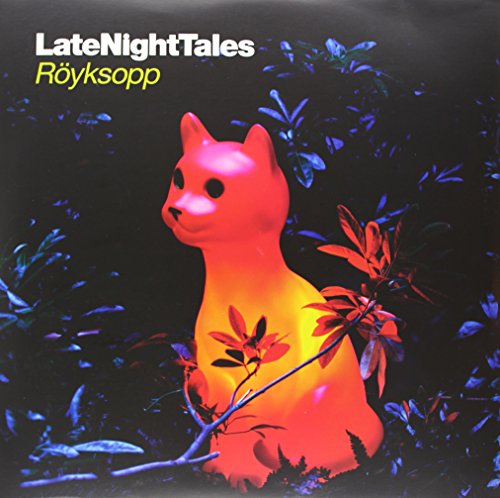 Red illuminated cat statue in dark foliage, album cover art.