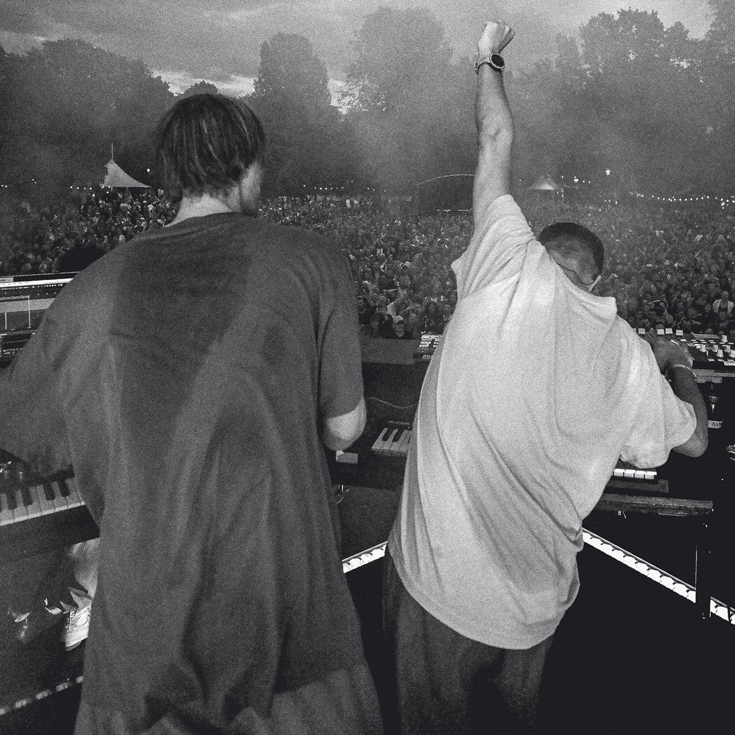 Black and white photo of two men performing at an outdoor concert with a crowd.