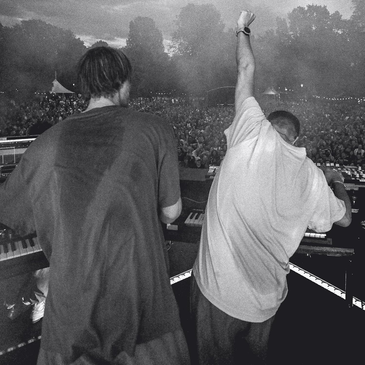 Black and white photo of two men performing at an outdoor concert with a crowd.