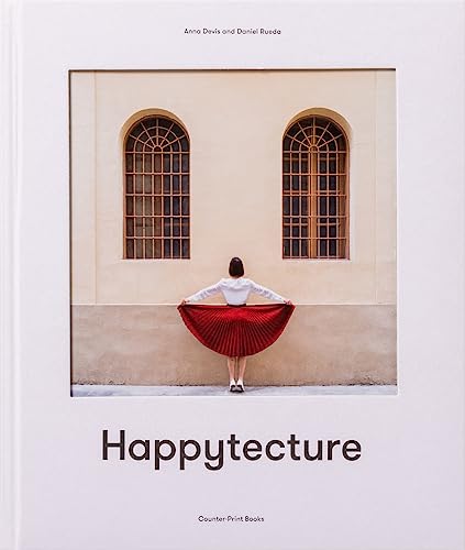 A person in a red pleated skirt stands before a building with arched windows.