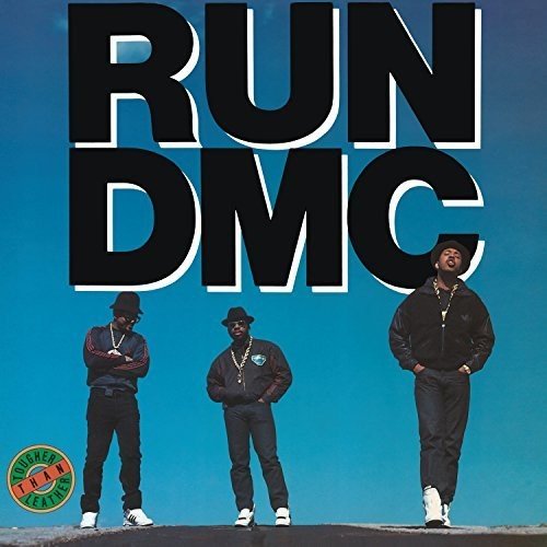 "Album cover featuring three men standing on a rooftop against a blue background."
