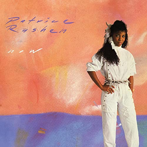 Patrice Rushen wearing a white jumpsuit against a painted orange and purple background.