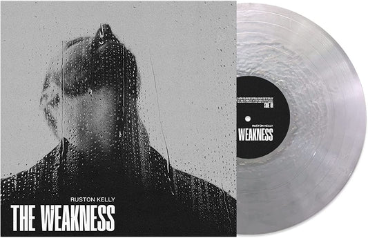 A vinyl record with a clear disc and a black label, alongside its album cover.