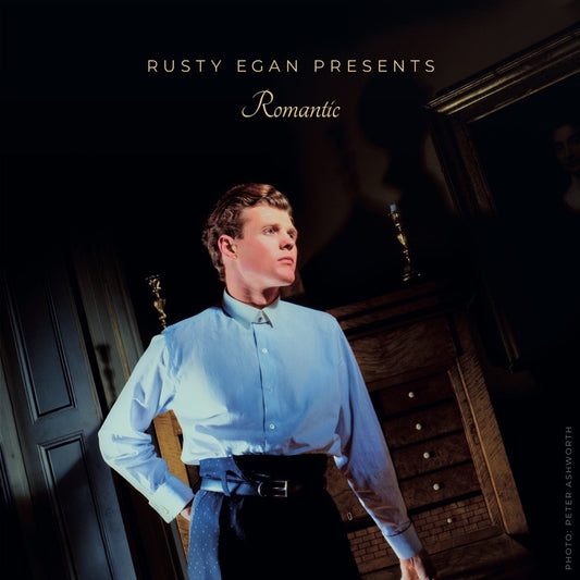 CD cover: man in blue shirt standing in a grand hallway.