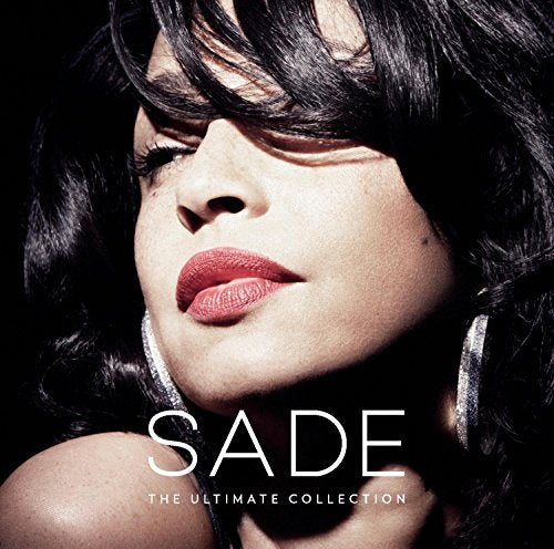 Close-up portrait of Sade with dark hair, red lips, and hoop earrings.