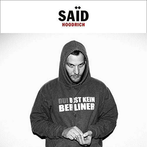 A man in a grey hoodie with text stands against a white background.