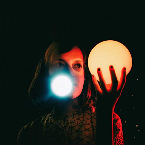 Woman holding a glowing orb in a dark, stylized portrait.