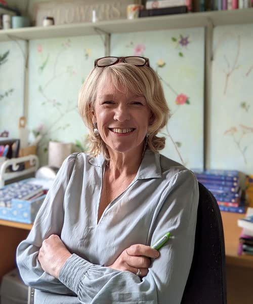 Smiling woman with short blonde hair, wearing glasses and a grey shirt.