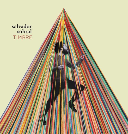 Album cover: Salvador Sobral stands amidst a colorful, cascading yarn structure.