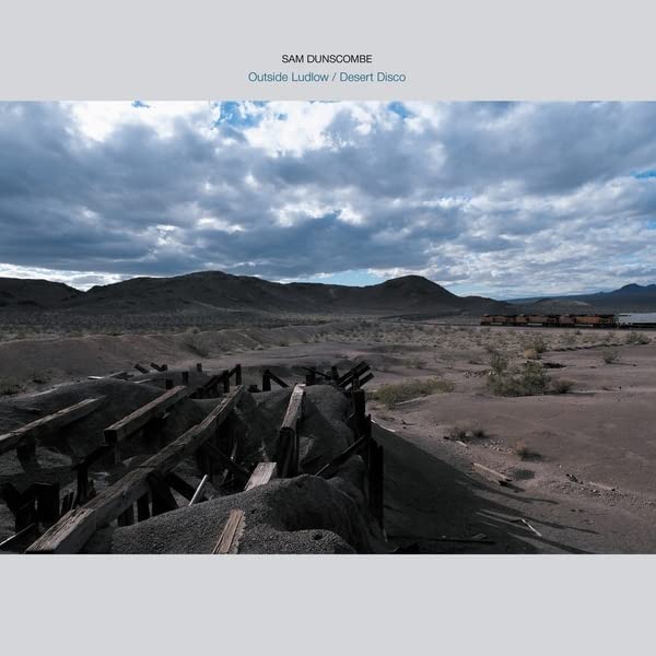 Vinyl album cover: desert landscape with ruins under cloudy sky.