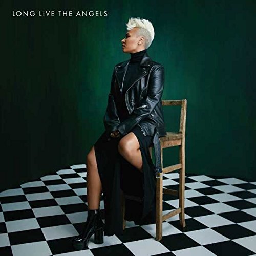 A woman with short white hair sits on a wooden chair against a checkered floor.