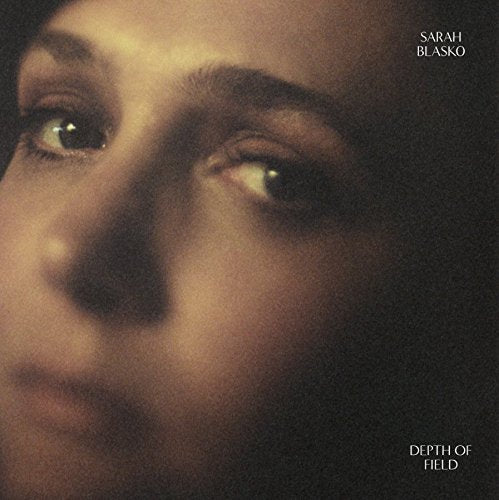 The alt text is: "Album cover with a close-up of a woman's face, dark background."