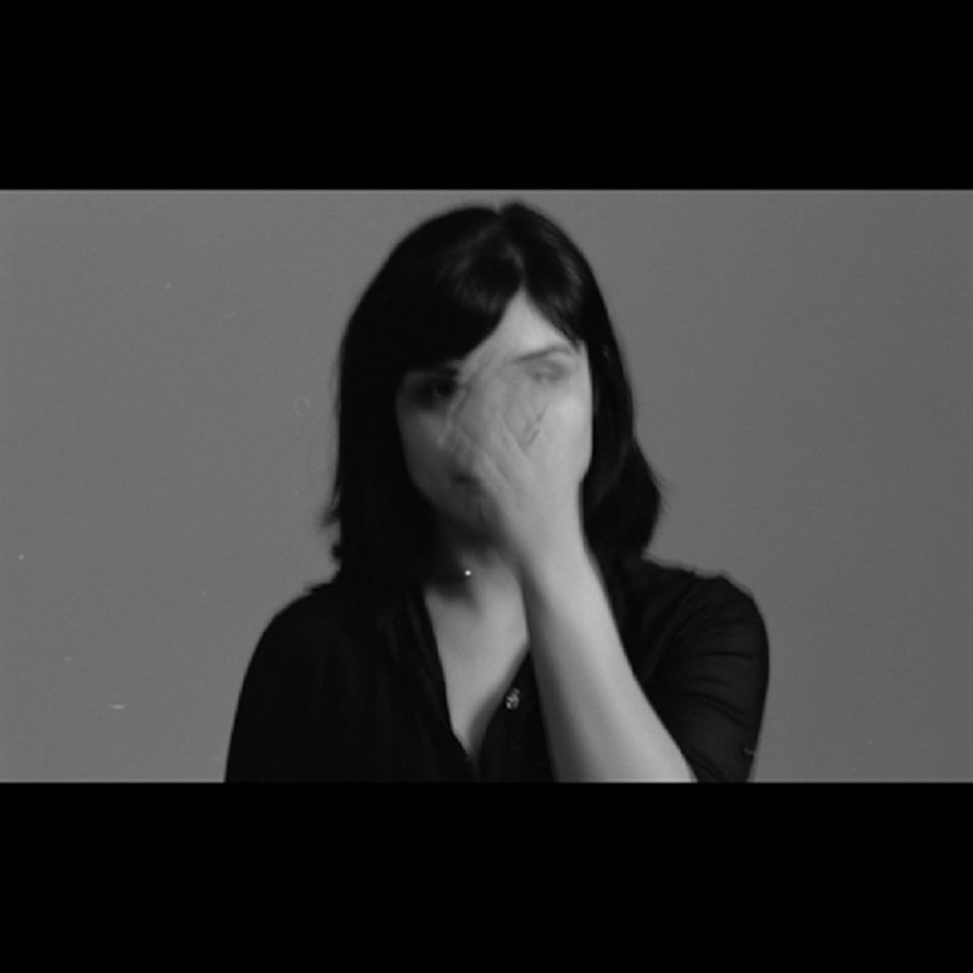 Black and white portrait of a woman with a motion-blurred hand covering her face.