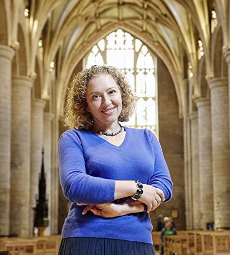 Woman with curly hair stands in a stone cathedral interior.