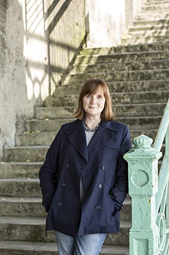 Woman in a dark coat stands on concrete steps outdoors.