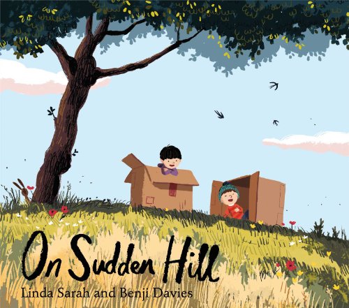 Two children play in cardboard boxes on a grassy hill under a large tree.