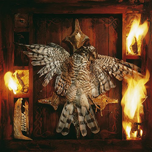 A hawk mounted on a cross against a dark wooden background with flames.