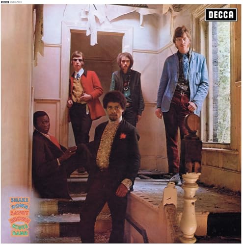 Five men in 1960s attire stand in a dilapidated, sunlit hallway of an old house.