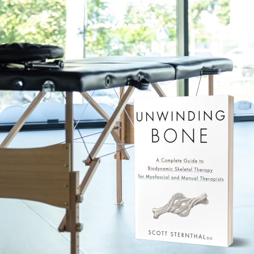Book titled “Unwinding Bone” rests on a massage table in a room.