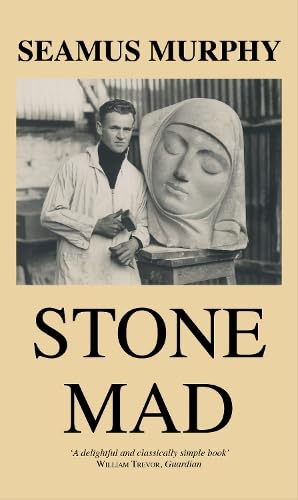 Black and white photo of a sculptor working beside a large stone head statue.