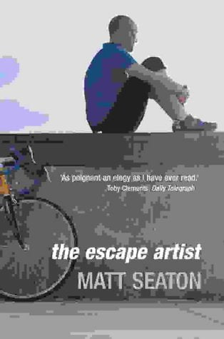 A man in a blue shirt sits on a wall beside a bicycle.