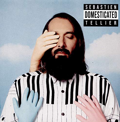 Bearded man in a striped shirt with hands covering his eyes and chest.
