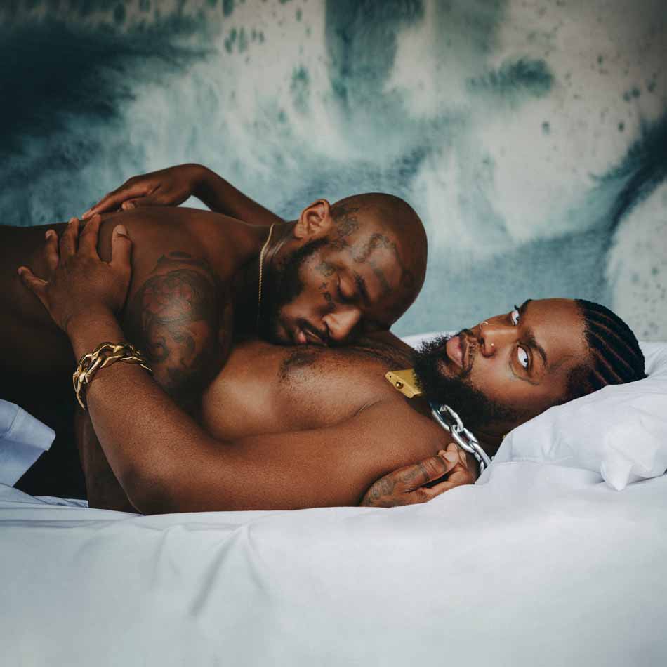 Two shirtless men embracing on a white bed, album artwork.