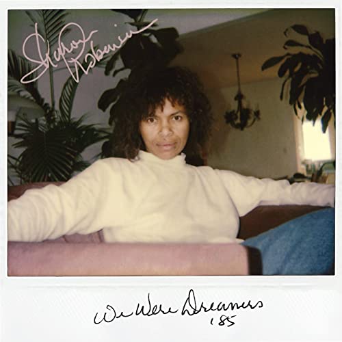 Sharon Robinson in a white sweater sitting in a room with plants and text.