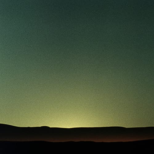 A grainy, dark landscape silhouette against a glowing, pale green horizon at dusk.