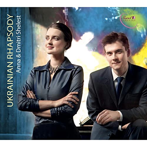 Anna and Dmitri Shelest posing in front of a colorful abstract background.