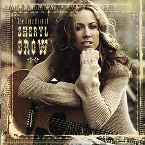 Sheryl Crow leans on an acoustic guitar wearing a tan sweater on her album cover.