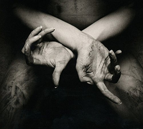 A black and white image of crossed, dirty hands against a dark background.