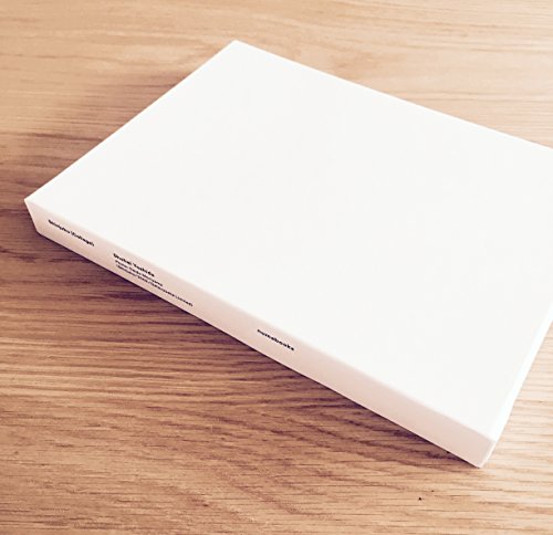 White rectangular box with text, resting on a light wood surface.