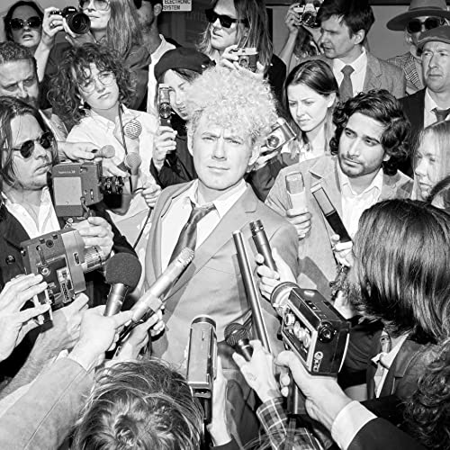 Black and white photo of Joe Ryan surrounded by cameras and microphones.