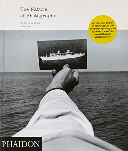 Book cover with a hand holding a photograph of a ship at sea.