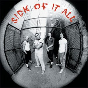 Four men stand in a narrow alleyway in this black and white fisheye photo.