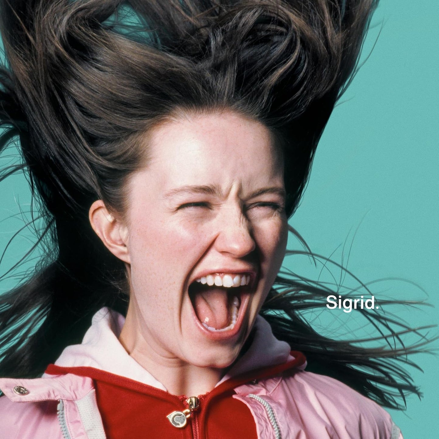 Woman with windswept hair screaming against a teal background.